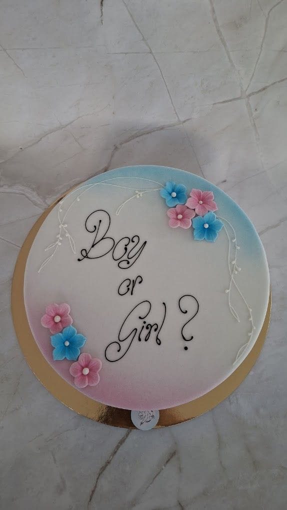 Runde Torte mit Boy-or-Girl-Schriftzug, rosa-blauem Airbrush-Verlauf und Zuckerblüten